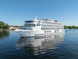 The large multi-deck cruise ship American Patriot gliding smoothly over calm blue water under a clear sky.