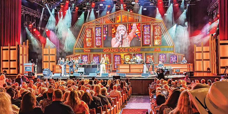 Audience watching live music performance at Grand Ole Opry, Nashville, with stage lights and musicians, part of American Cruise Lines river cruise excursion.