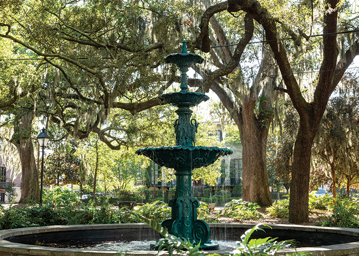 Fountain in Lafayette Square, Savannah, Georgia, a historic port stop, surrounded by large trees and hanging moss.
