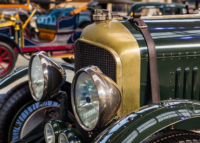 Vintage car with brass radiator and large headlights, displayed indoors at the Fountainhead Antique Auto Museum.