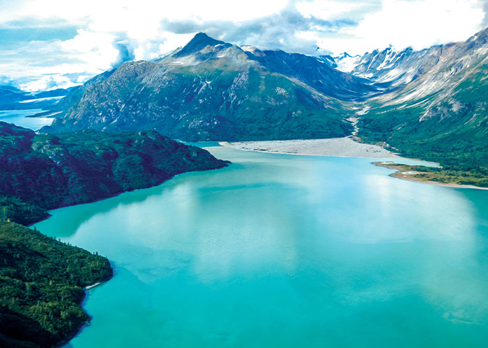 Glacial waters and snow-covered peaks in Glacier Bay National Park viewed from a small ship Alaska cruise offering immersive scenic cruising