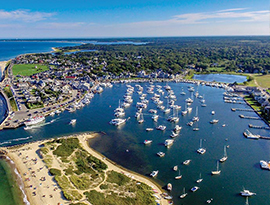 Aerial view of a harbor with many boats, sandy beaches, green coastline, and a small town, ideal for American Cruise Lines river cruises.