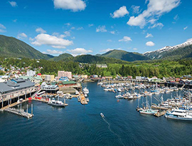 Scenic Alaska harbor with small cruise ships and forested mountain backdrop