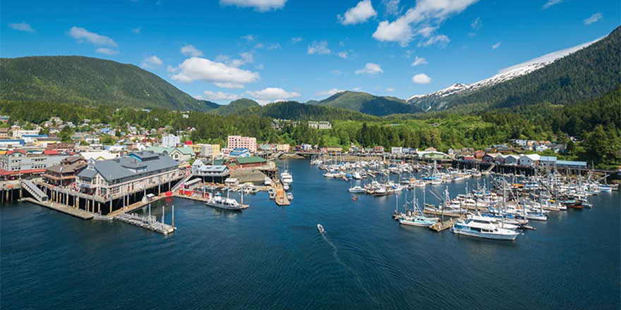 Alaska waterfront town with a busy marina surrounded by forested mountains